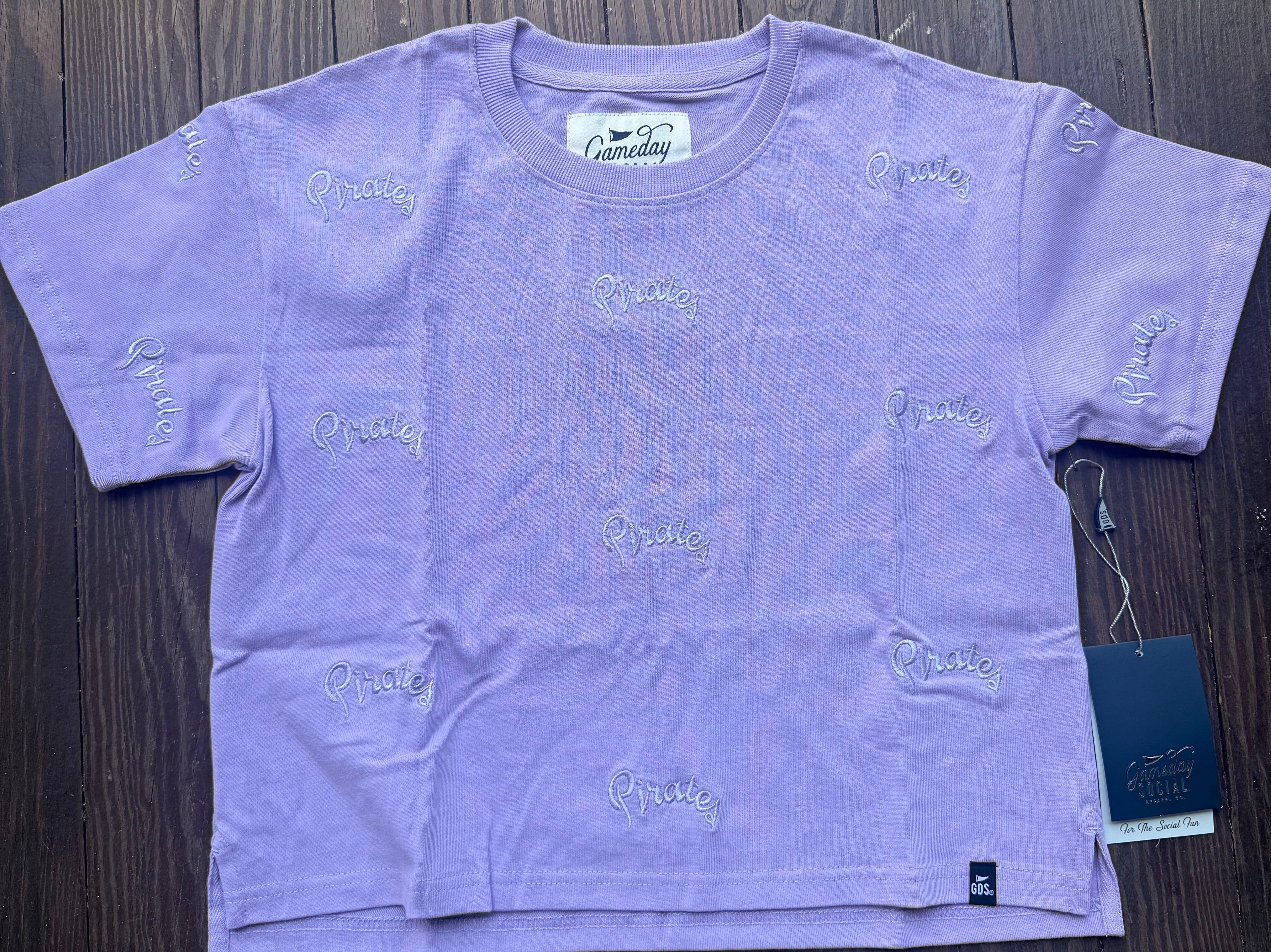 A lavender purple short-sleeve t-shirt by Everyday, featuring an all-over embroidered script logo pattern.