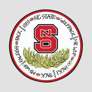 Circular NC State Wolfpack logo with red 'NC' and green leaves plates on a gray background