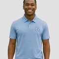 Man wearing a light blue polo shirt with an UNC logo on a gray background