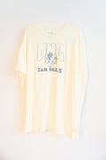 A pale beige short-sleeve t-shirt with a light blue graphic print on the front reading 'UNC TAR HEELS' with a ram mascot logo, displayed against a plain white background.