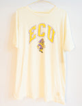 A cream-colored short-sleeve t-shirt hanging on a hanger against a white wall, featuring a yellow and purple 'ECU' graphic with the Texas Longhorns mascot on the front.