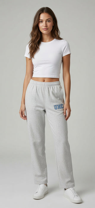 Woman wearing light gray sweatpants with a UNC embroidered logo on a plain background