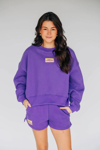 A woman modeling ECU purple shorts with small yellow brand patch on the right bottom of shorts.