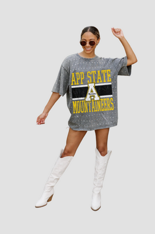 Person wearing a gray rhinestone 'APP STATE MOUNTAINEERS' t-shirt with white knee-high boots on a light gray background