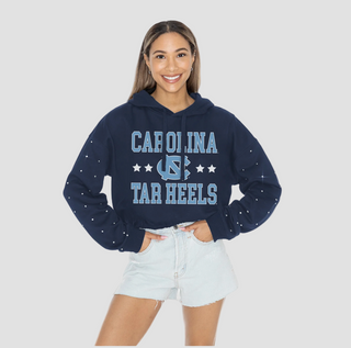 Person wearing a navy blue cropped 'Carolina Tar Heels' hoodie on a light gray background