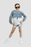 Child wearing a gray sweatshirt with 'UNC' and denim shorts on a light gray background