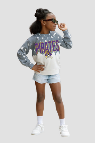 Girl wearing a 'Pirates' sweatshirt with a white shirt and denim shorts on a light gray background
