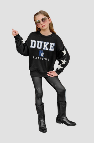Girl wearing a Duke Blue Devils sweatshirt with star designs on a white background